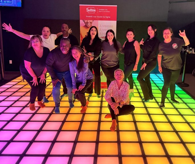 A corporate team posing on the rainbow-lit jeuLumi floor after a team-building session